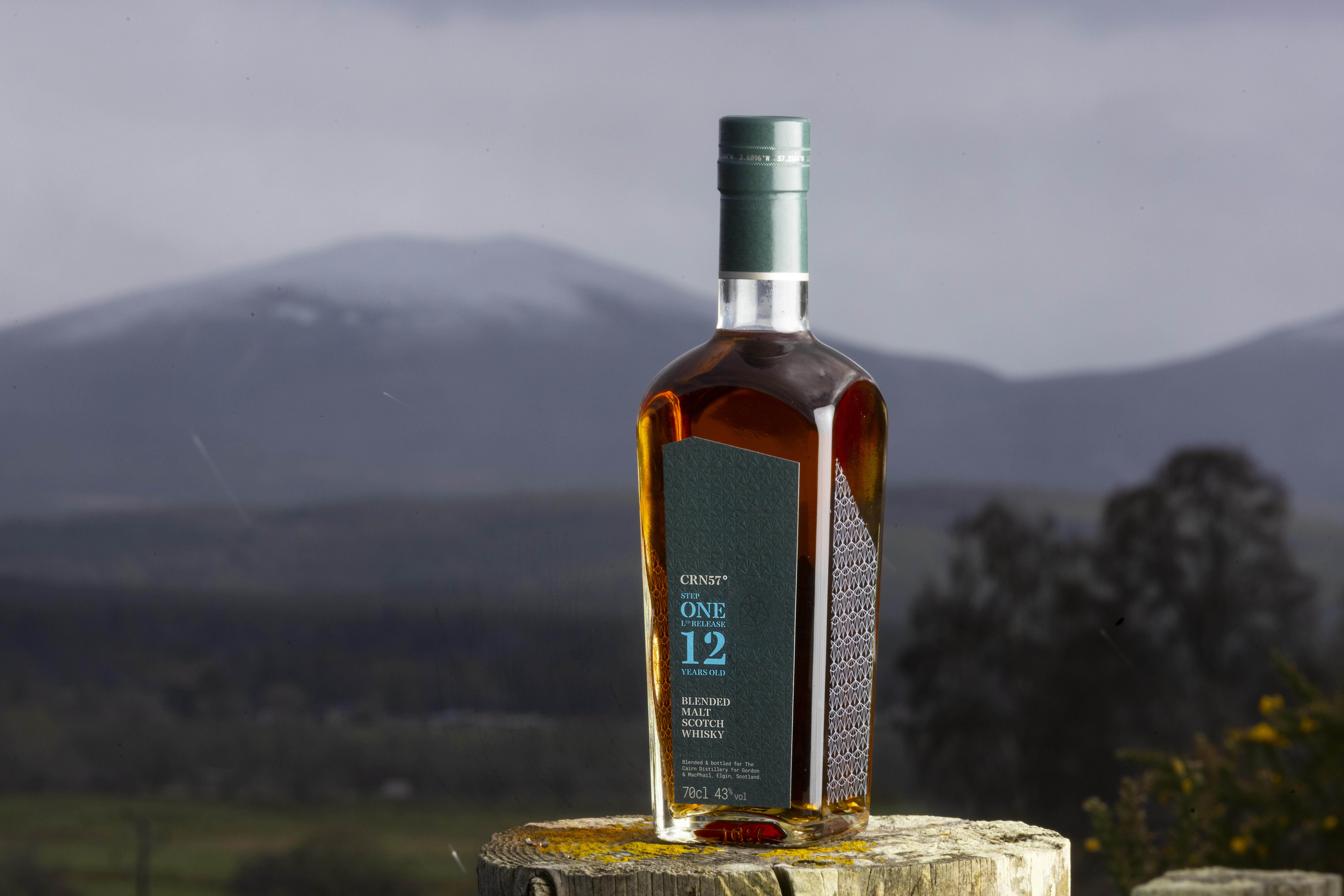 A bottle of CRN57 12 years old Step One blended malt Scotch whisky with a hill in the background