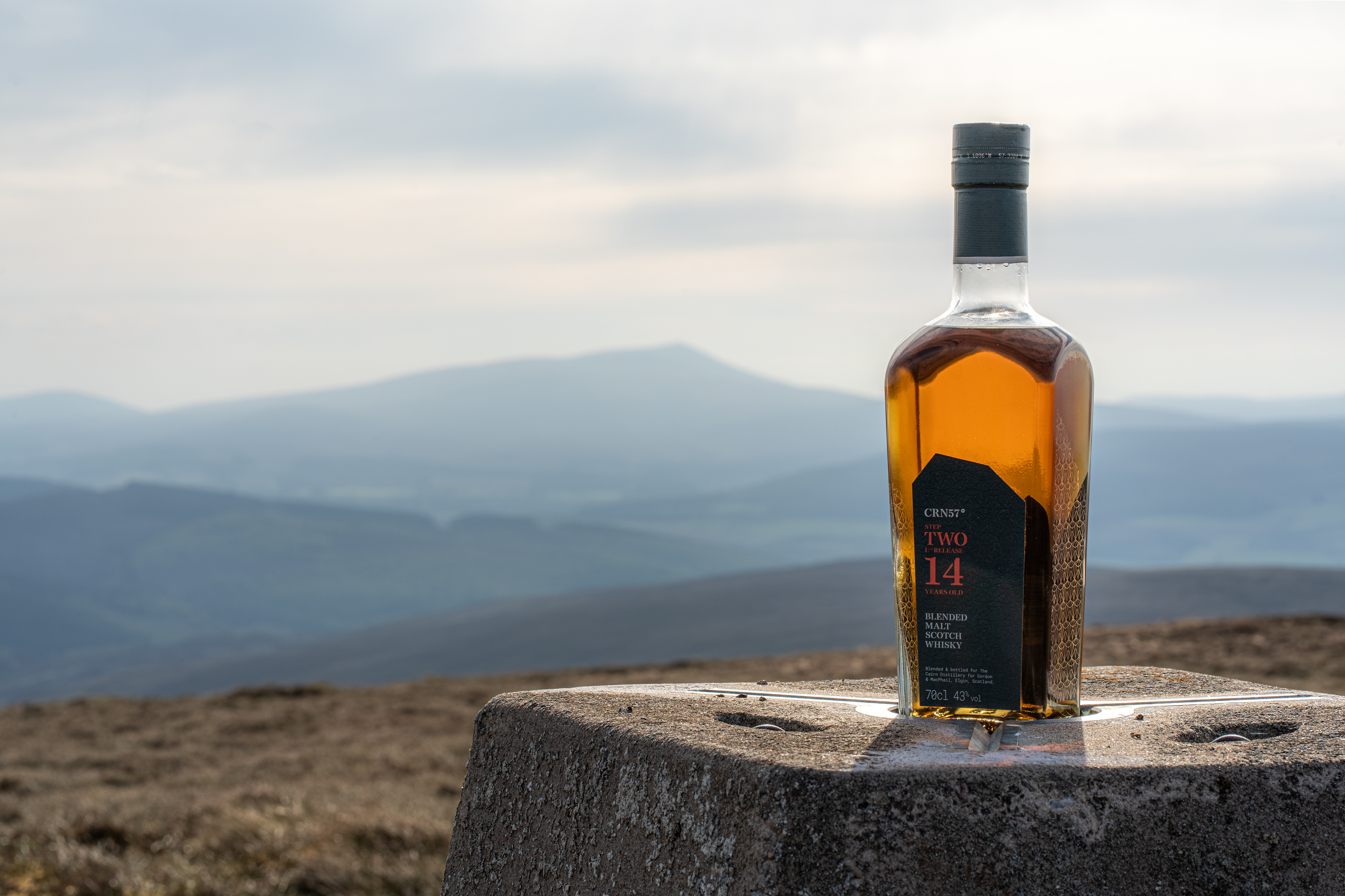 A bottle of CRN57 14 years old Step Two with a hill in the background